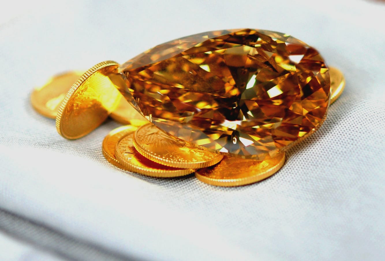 Fancy Yellow Diamant auf Goldmünzen als symbolischer Vergleich zweier Wertanlagen