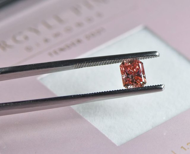 Ein natürlicher Fancy Colour Diamant in der Diamantenzange über einer Karte des Argyle Tenders