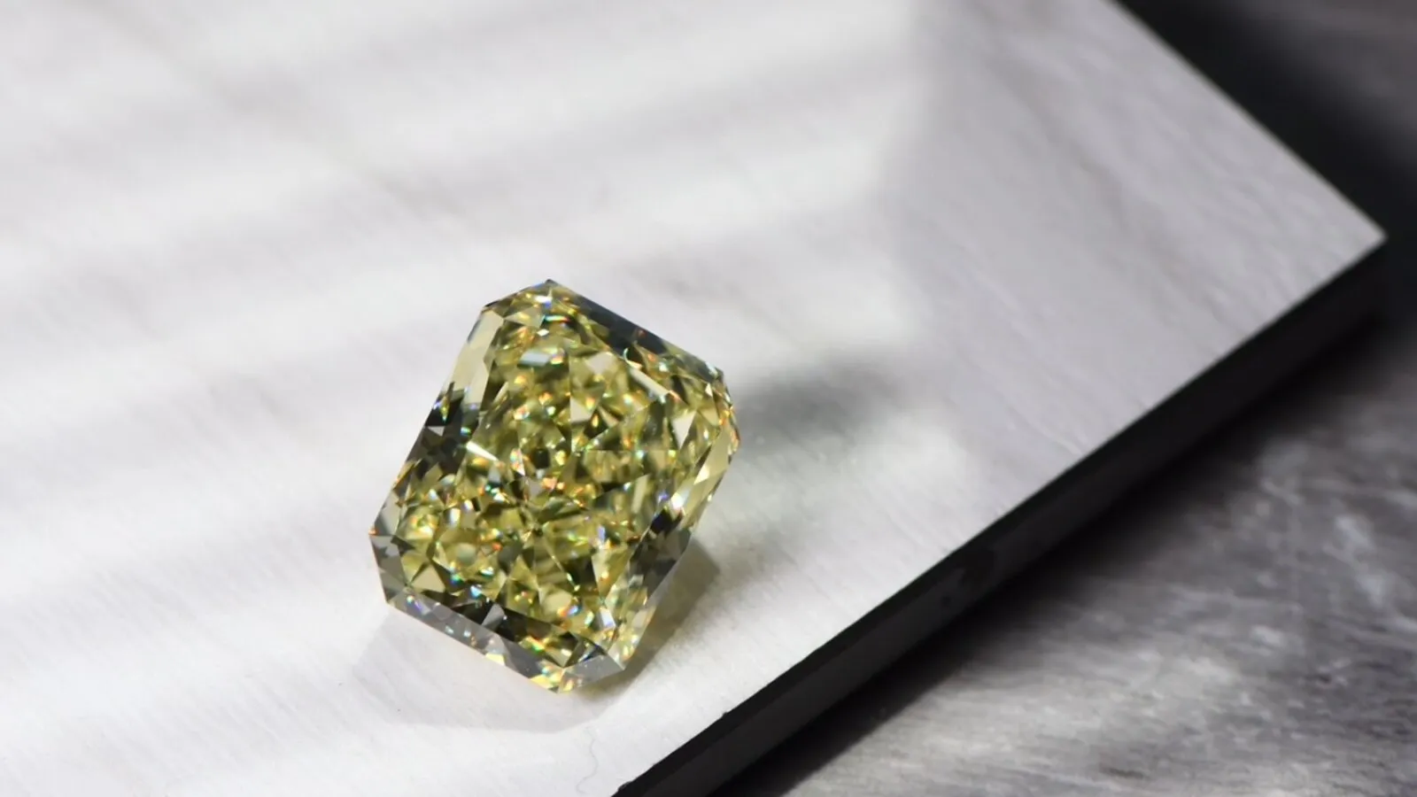 Natürlicher Fancy Vivid Yellow Diamant im Radiant Schliff auf hellem Untergrund